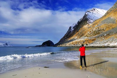 Rear view of man standing on beach against sky