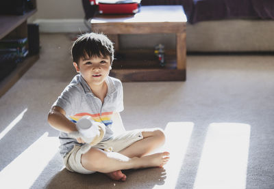 Cute baby boy sitting on floor at home