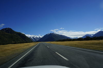 Road by mountains against blue sky