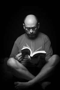 Portrait of man sitting against black background