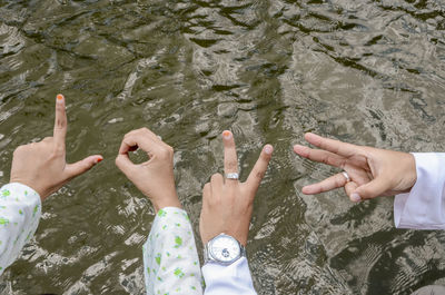 Cropped friends gesturing above lake