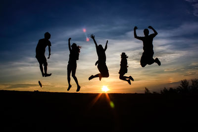 Silhouette people jumping against sky during sunset