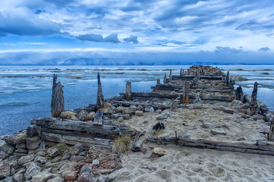 Driftwood on beach by sea against sky