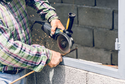 Midsection of construction worker cutting metal