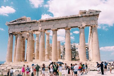 Low angle view of tourists at historical building against sky