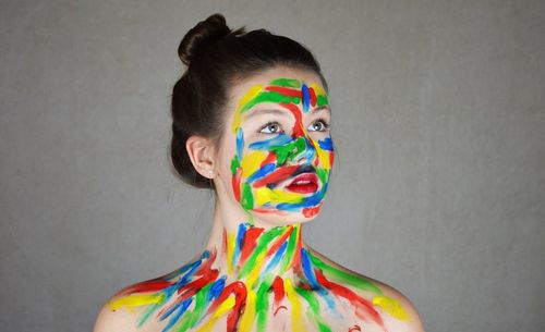 Young woman with face paint against gray background