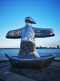 Statue by sea against clear blue sky