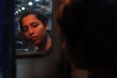 Young woman reflecting on mirror in train