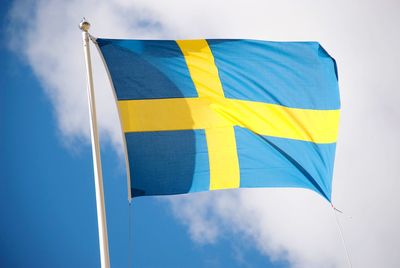 Low angle view of swedish flag against blue sky