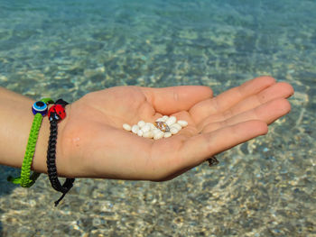 High angle view of woman hand holding pebbles in water