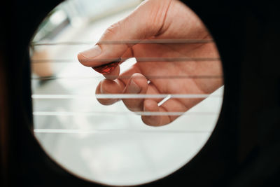 Close-up of hand playing guitar at home