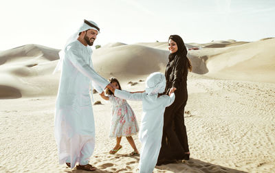 Happy family playing on sand dune