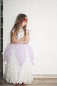 Young woman standing against white wall