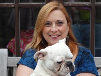 Portrait of smiling woman with french bulldog sitting on bench outdoors