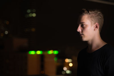 Portrait of young man looking away at night