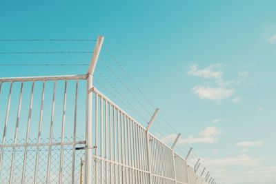 Low angle view of fence against blue sky