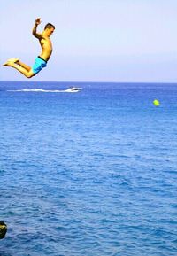 Man jumping in sea against clear sky