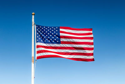 Low angle view of flag against clear blue sky