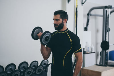 Determined young man working out in gym. fit male doing exercise with weights for biceps. sporty man