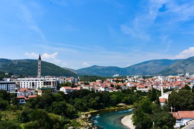 Townscape by mountains against blue sky