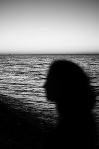 Silhouette person against sea against clear sky