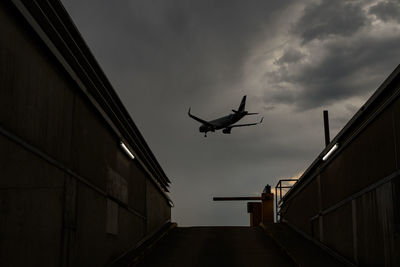 Low angle view of silhouette airplane flying against sky and a boom barrier. 