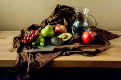 High angle view of fresh fruits with water and knife on table