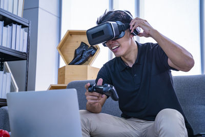 Man playing video game wearing virtual simulator while sitting at home