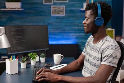 Side view of young man using laptop at table