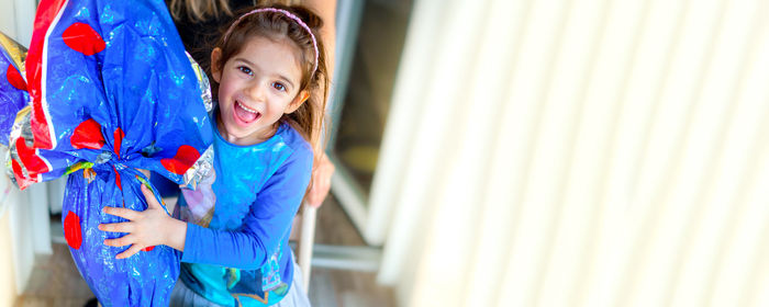 Portrait of smiling girl standing against wall