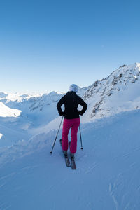 Rear view of woman skiing on snowcapped mountain against sky