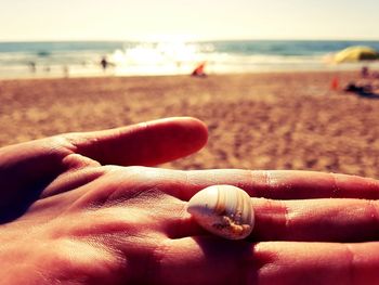 Close-up of hands on sand at beach