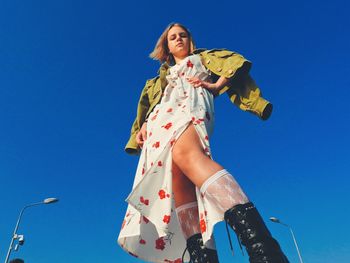 Low angle view of woman against blue sky