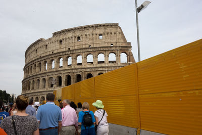 People at historic coliseum against sky