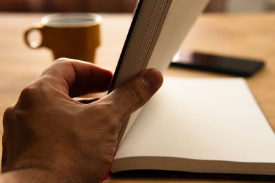 Cropped hand of person using mobile phone at table