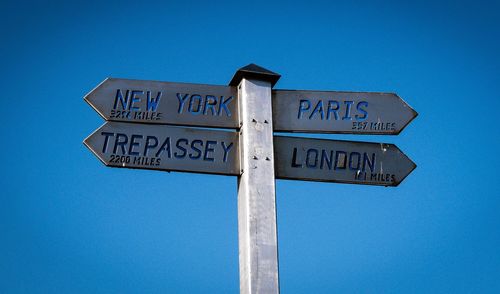 Low angle view of road sign against clear blue sky