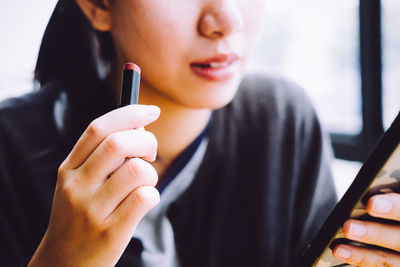 Close-up of woman holding lipstick