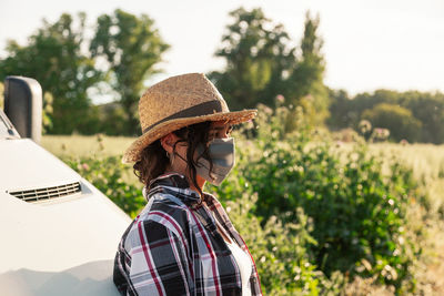 Side view of woman wearing mask while standing outdoors