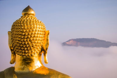 Statue of buddha and building against sky