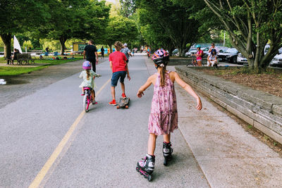 People walking, riding bike, skateboarding, roller skating on the road in city park