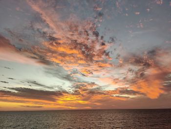 Scenic view of sea against dramatic sky during sunset