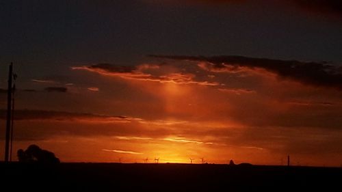 Silhouette landscape against dramatic sky during sunset