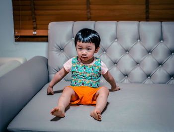 Portrait of boy sitting on sofa at home