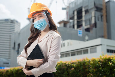 Young woman wearing hat standing against built structure