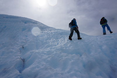 Low angle view of people on glacier against sky