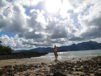 Woman standing on beach against sky