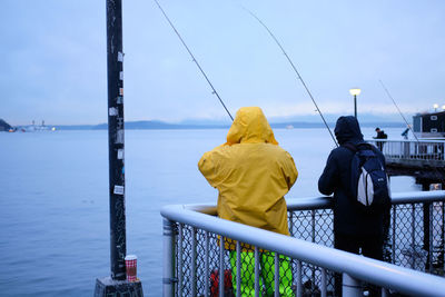 Rear view of people fishing on pier
