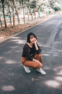Portrait of young woman sitting on road in city