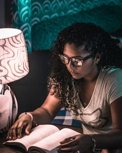 Woman reading book while sitting at table