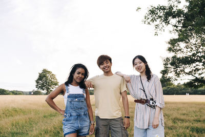 Smiling friends standing together at park